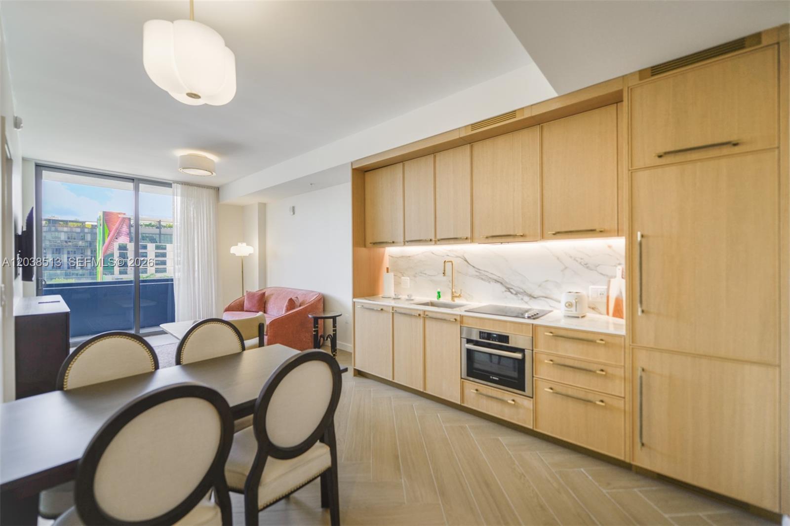 A modern kitchen with light wood cabinetry and marble backsplash opens into a dining area — 2700 NW 2nd Ave # 509, Miami FL 33127, MIAMI, FL