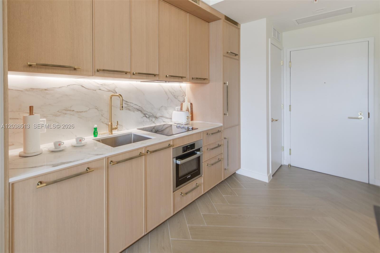 A modern kitchen features light wood cabinetry, marble countertops, a gold faucet, and herringbone flooring — 2700 NW 2nd Ave # 509, Miami FL 33127, MIAMI, FL