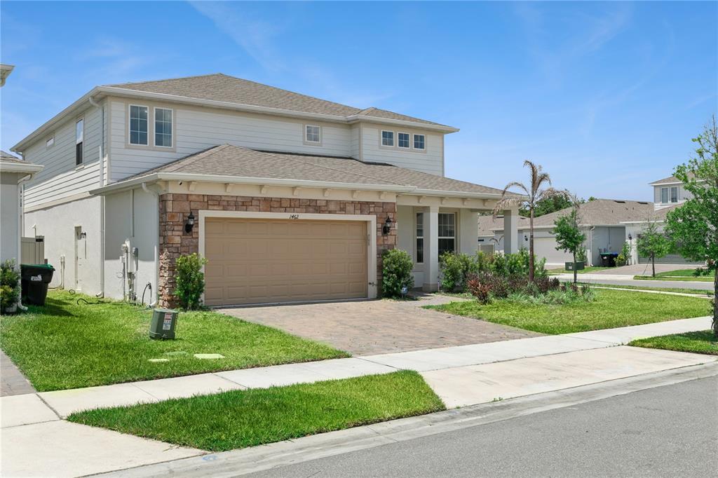 A two-story house with a stone-accented facade, a two-car garage, and a paved driveway — 1462 GRAND PALM DRIVE, ORLANDO, FL