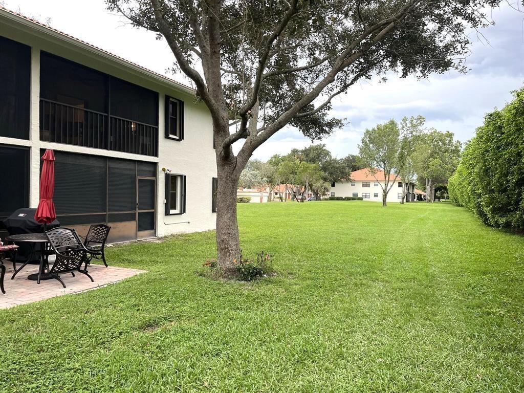 A patio with furniture sits beside a two-story building overlooking a large grassy yard — 9807 Pavarotti Terrace, Boynton Beach FL 33437, BOYNTON BEACH, FL