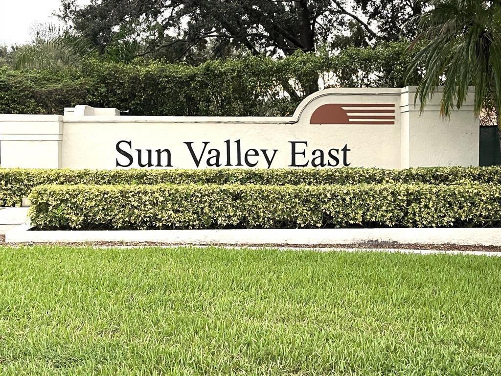 A beige monument sign for Sun Valley East sits behind a manicured hedge and lawn — 9807 Pavarotti Terrace, Boynton Beach FL 33437, BOYNTON BEACH, FL