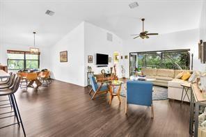 An open-concept living and dining area with vaulted ceilings, wood-look flooring, and a large sectional — 9807 Pavarotti Terrace, Boynton Beach FL 33437, BOYNTON BEACH, FL
