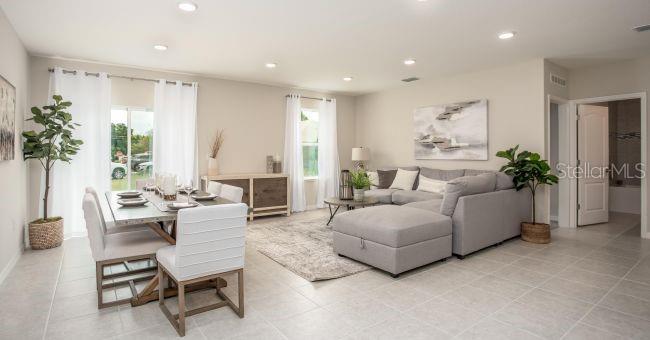 An open-concept living and dining area with light tile floors, a sectional sofa, and furniture — 3 PORTER LANE, PALM COAST, FL