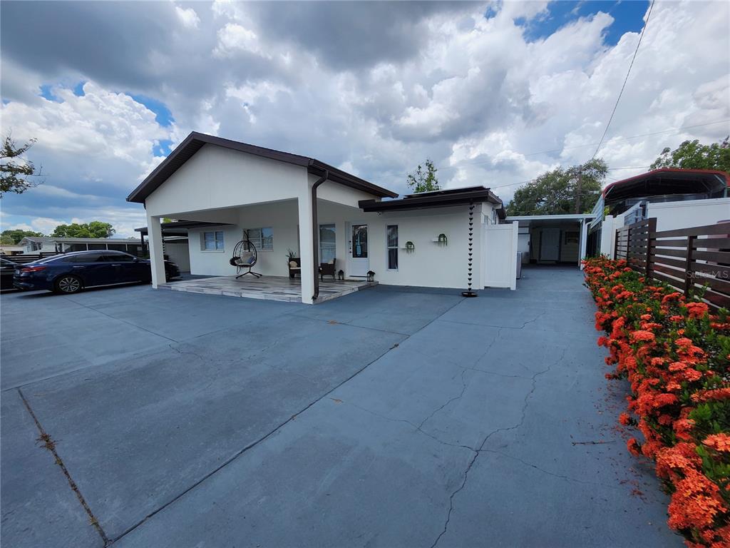 A white house with a covered patio and a large paved driveway — 7514 PARADISE PLACE, TAMPA, FL