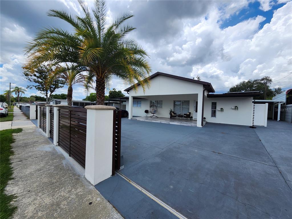 A single-story house with a large concrete driveway, a covered porch, and a palm tree — 7514 PARADISE PLACE, TAMPA, FL