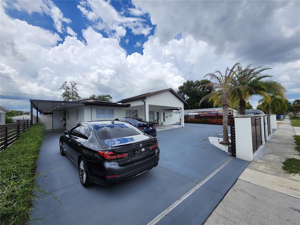 A black sedan is parked on a paved driveway in front of a white house — 7514 PARADISE PLACE, TAMPA, FL