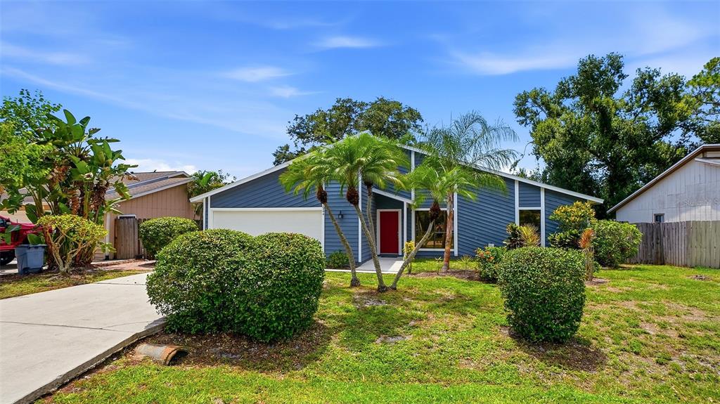 A blue, single-story house with a red front door, palm trees, and a concrete driveway — 3944 PALAU DRIVE, SARASOTA, FL
