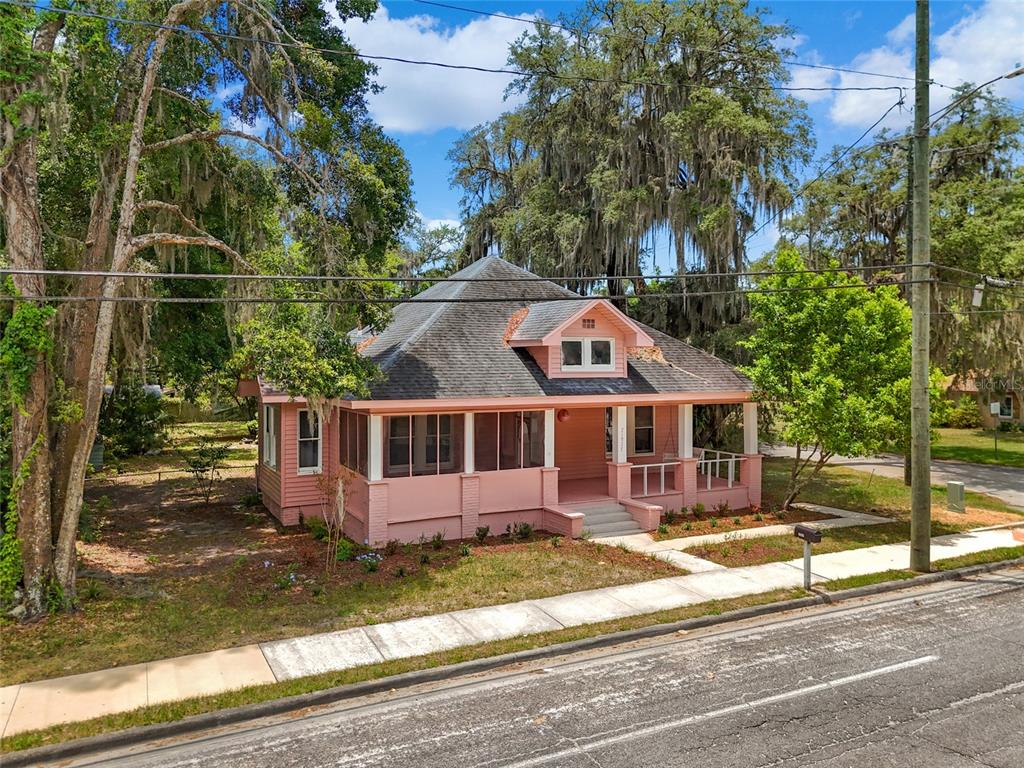 A pink, single-story house with a screened-in porch sits on a corner lot with trees — 21927 SE 69TH AVENUE, HAWTHORNE, FL