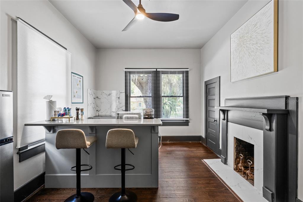 A kitchen with a gray island, bar stools, and a fireplace with a black mantel — 21927 SE 69TH AVENUE, HAWTHORNE, FL