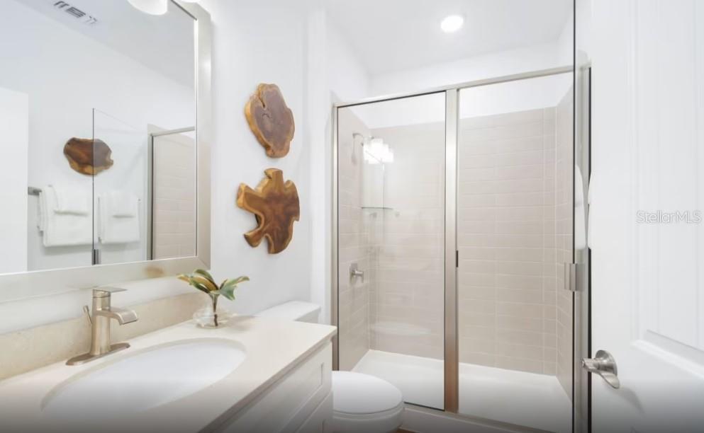 A bathroom features a vanity with a sink, a glass-enclosed shower, and wood wall decor — 4782 W BLUE STAR COURT, NORTH PORT, FL