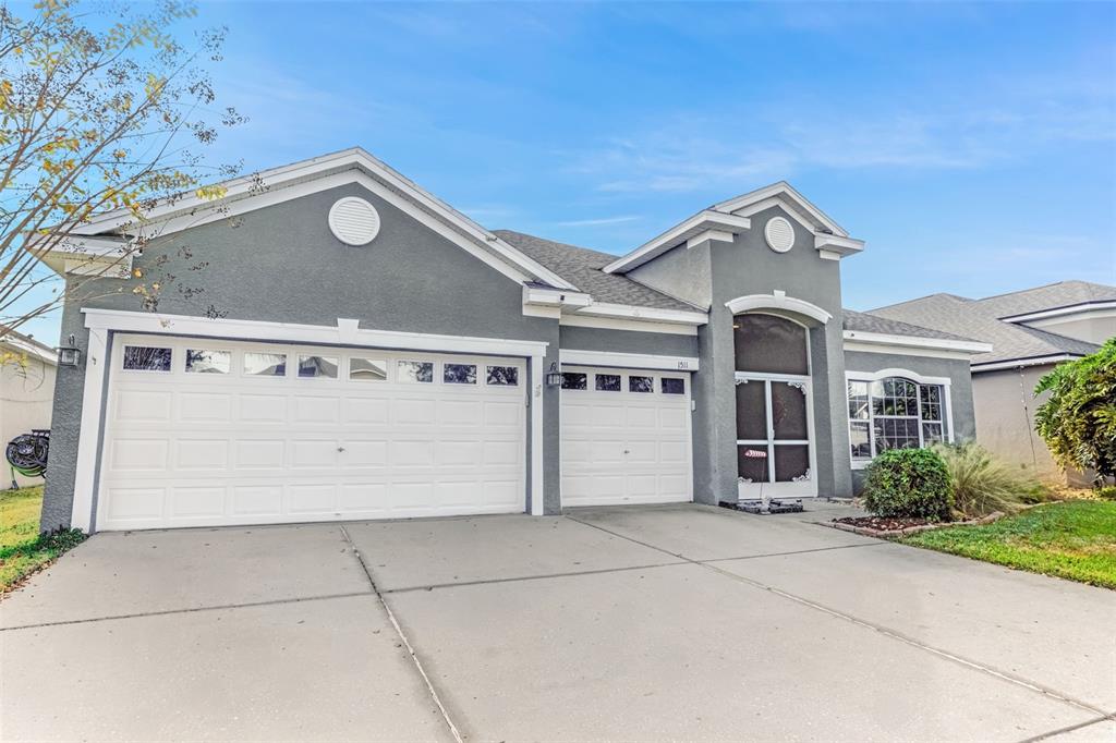 A gray single-story house with a three-car garage and a screened front entryway — 1511 BONITA BLUFF COURT, RUSKIN, FL