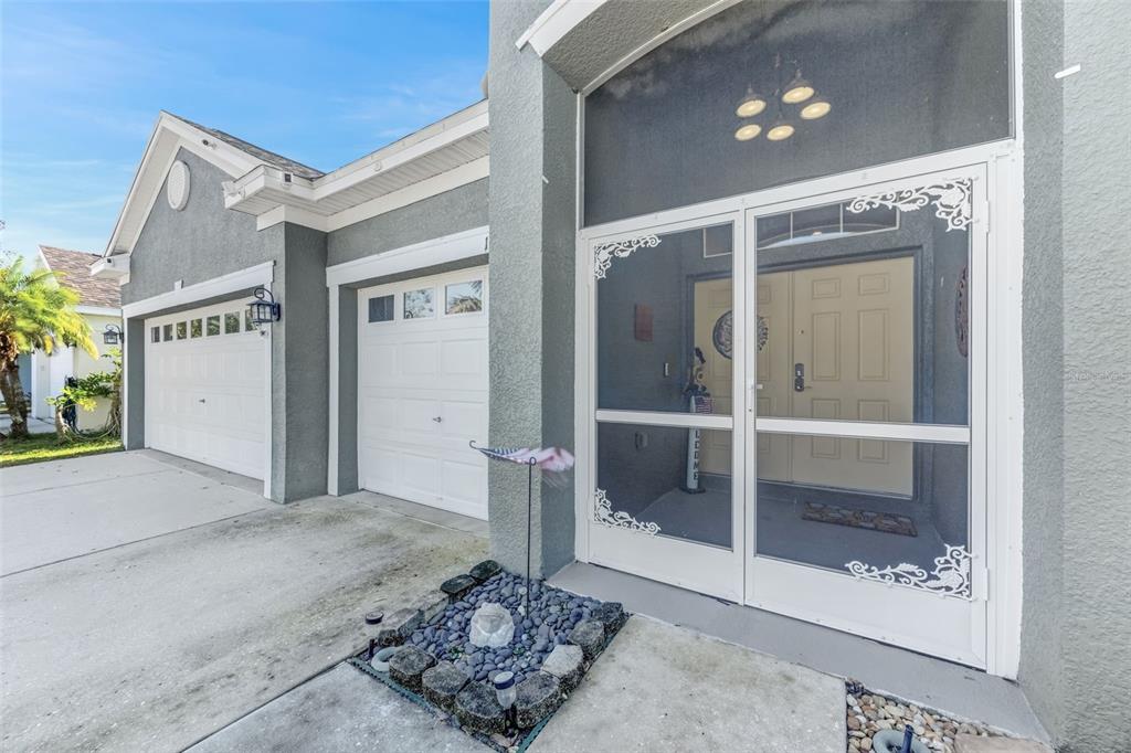 The exterior of a house features a two-car garage and a screened-in front entryway — 1511 BONITA BLUFF COURT, RUSKIN, FL