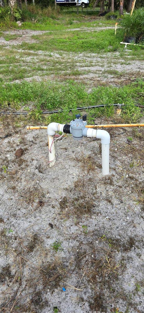 An irrigation control valve is installed on white PVC pipes protruding from sandy ground — 15720 Okeechobee Boulevard, FL 33470, FL