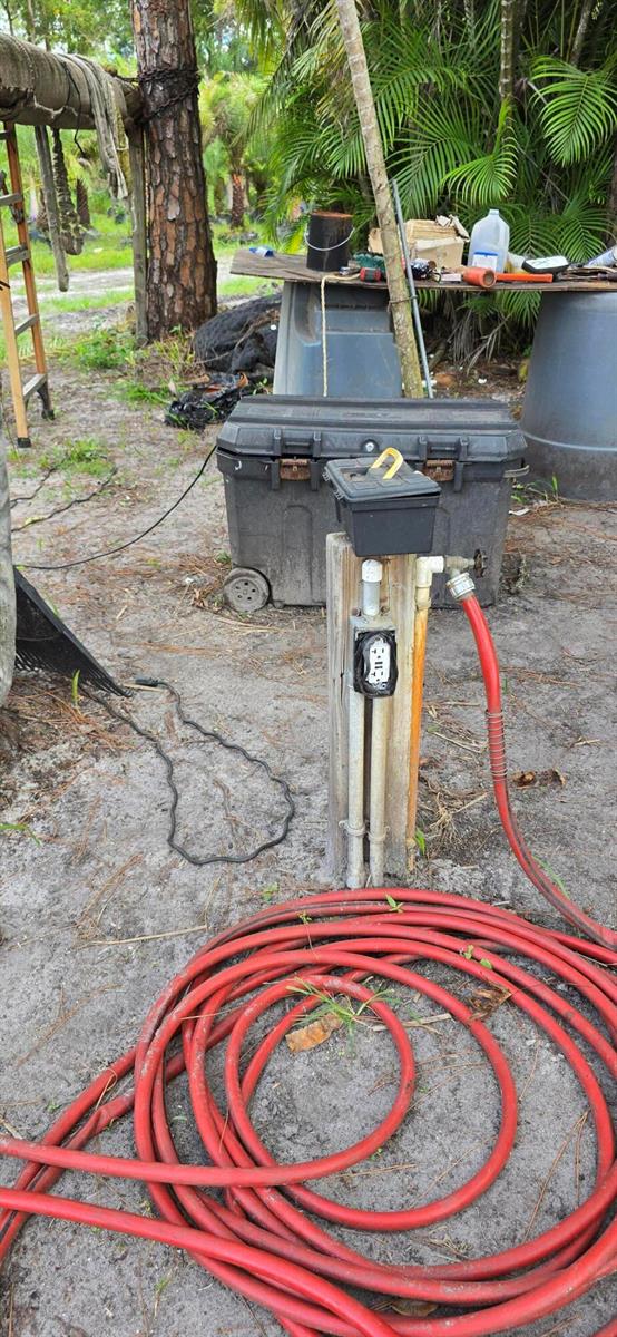 An outdoor wooden post features an electrical outlet and a water spigot with a hose — 15720 Okeechobee Boulevard, FL 33470, FL