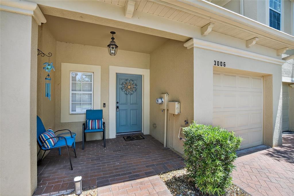 A covered brick entryway features a blue front door, two chairs, and a garage — 3006 GIRVAN DRIVE, LAND O LAKES, FL