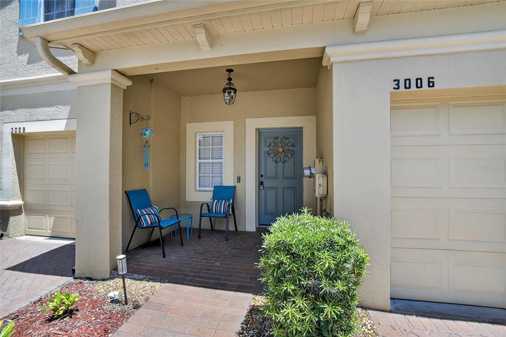 The exterior of a home features a covered porch, two chairs, and a garage door — 3006 GIRVAN DRIVE, LAND O LAKES, FL