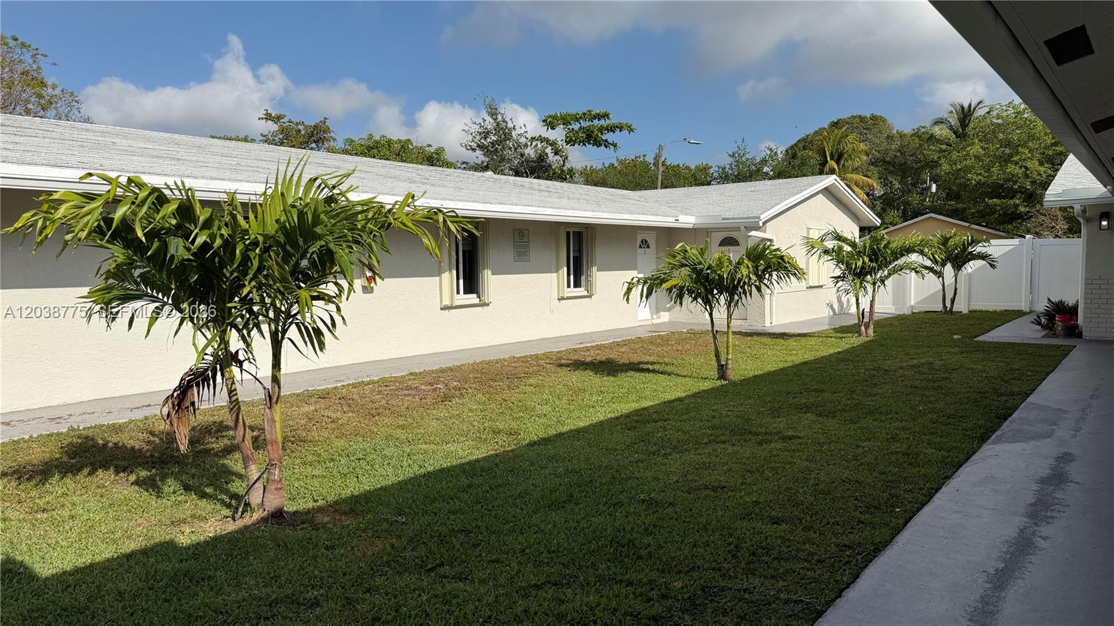 A single-story building with a light-colored exterior, a grassy yard, and several small palm trees — 220 NW 12th St # 4, Pompano Beach FL 33060, POMPANO BEACH, FL