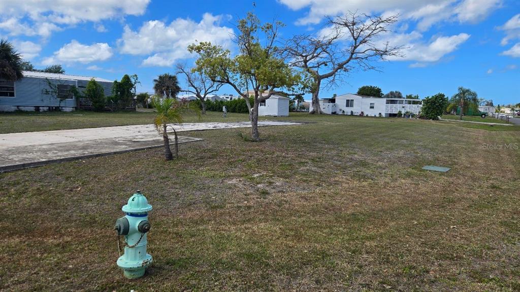 A light blue fire hydrant stands in the foreground of a grassy residential lot — 1464 BLUE HERON DRIVE, ENGLEWOOD, FL