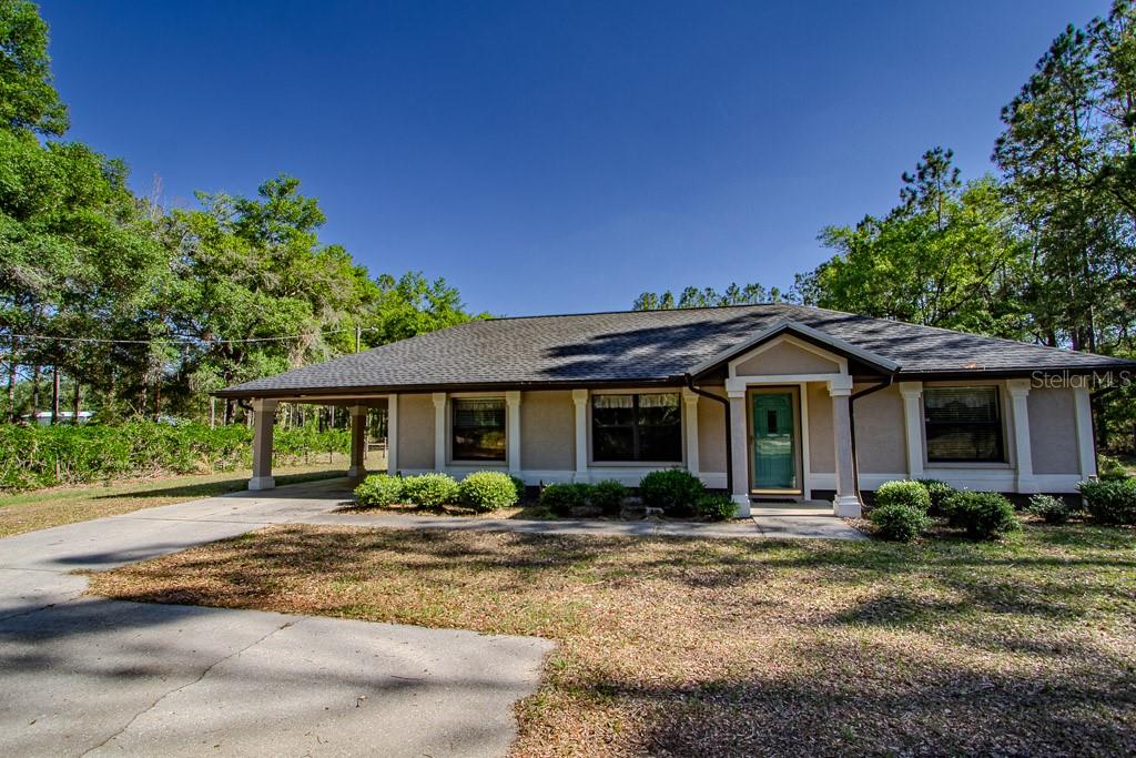 A single-story house with a beige exterior, a covered carport, and a front entrance porch — 4002 SW COUNTY ROAD 18, FORT WHITE, FL