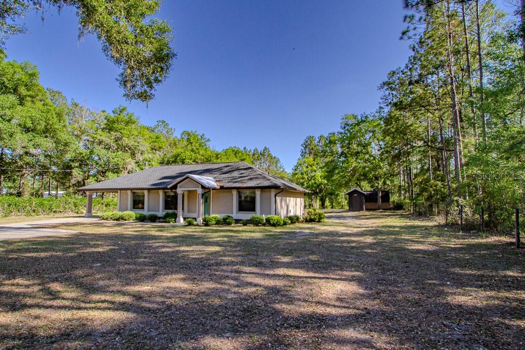 A single-story house with a covered porch sits on a large, wooded lot — 4002 SW COUNTY ROAD 18, FORT WHITE, FL