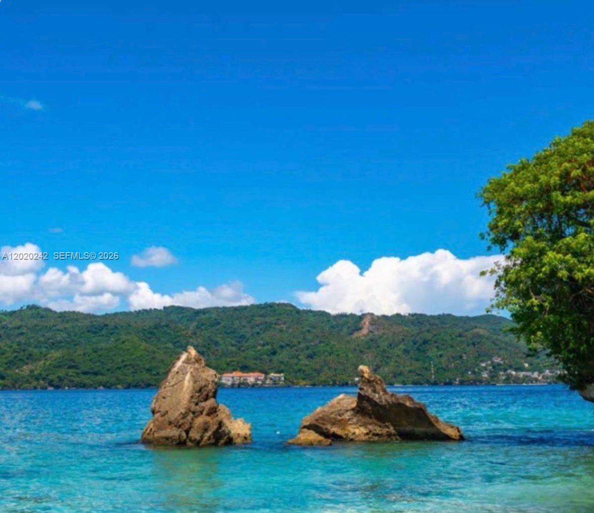 Two large rock formations rise from the turquoise water before a forested mountain range — SAMANA, SANCHEZ-LOS ROBALOS, FL, FL