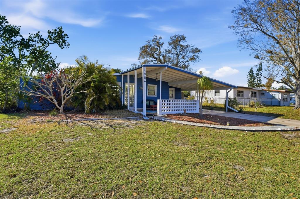 A blue single-story house features a front carport and a white decorative concrete block wall — 1904 31ST STREET W, BRADENTON, FL