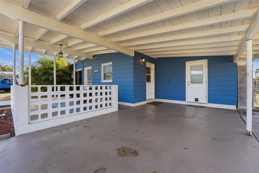 A blue house exterior features a covered carport with a white concrete block privacy wall — 1904 31ST STREET W, BRADENTON, FL