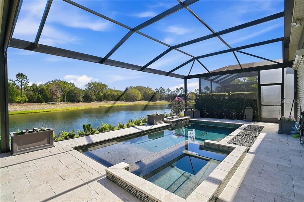 A screened-in patio features a rectangular swimming pool and spa overlooking a lake — 14911 CASTLE PARK TERRACE, LAKEWOOD RANCH, FL