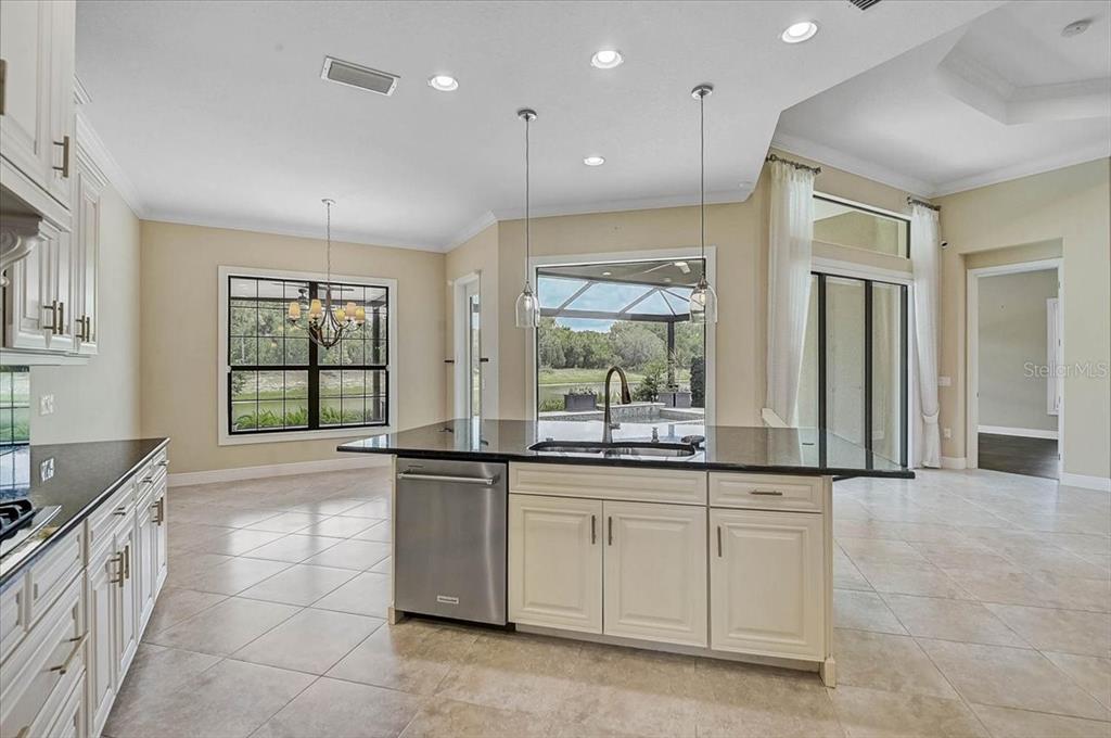 A kitchen with white cabinets, a black granite island, and a view of a pool — 14911 CASTLE PARK TERRACE, LAKEWOOD RANCH, FL