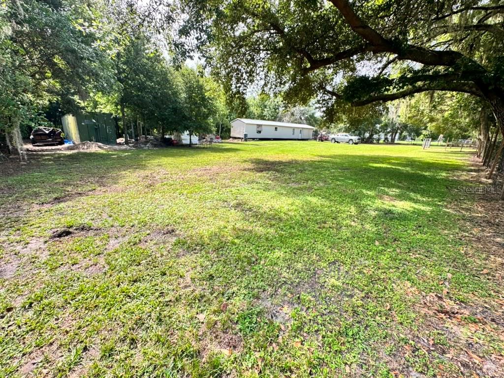 A large, grassy backyard features mature trees, a storage shed, and a mobile home — 3904 CORK ROAD, PLANT CITY, FL