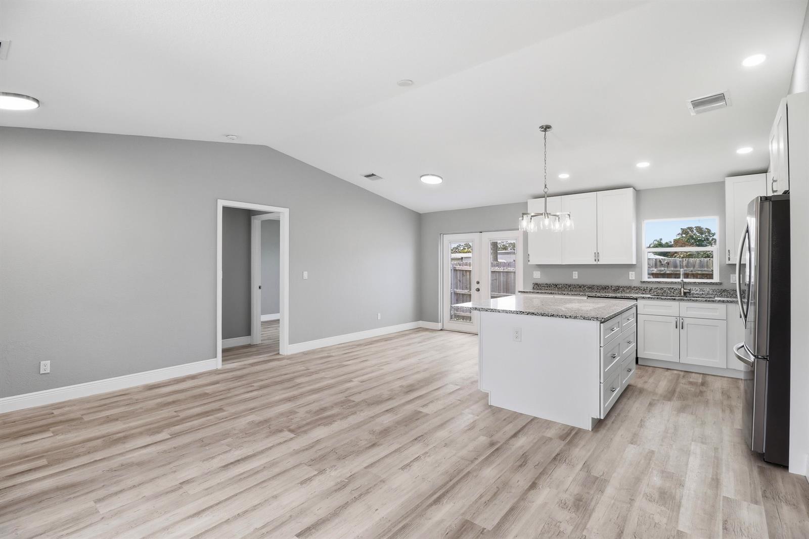 A kitchen and living area with gray walls, light wood flooring, and a granite island — 2805 SE Carroll Street, Stuart FL 34997, STUART, FL