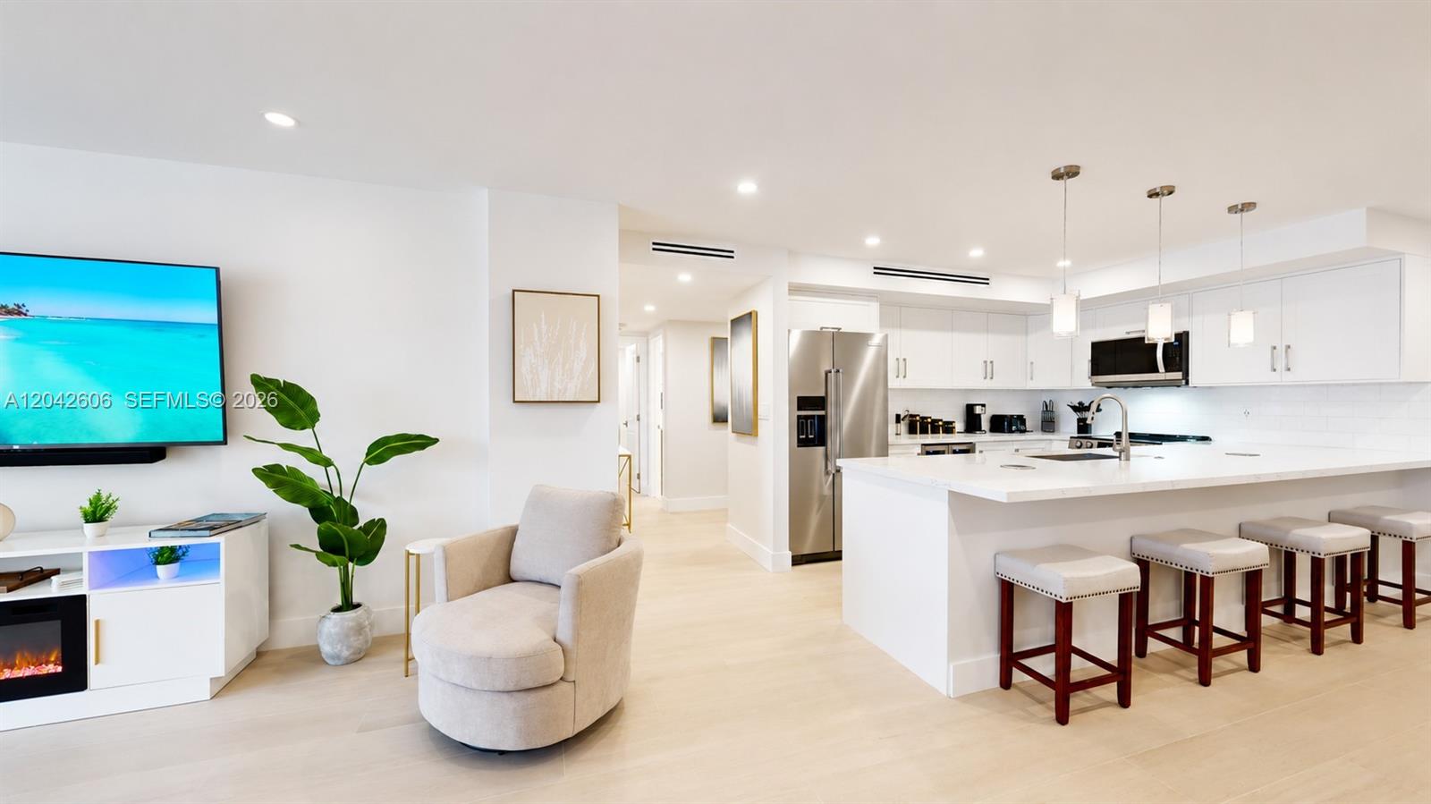 A modern, open-concept kitchen and living area features white cabinetry, a large island, and flooring — 177 Ocean Lane Dr # 213, Key Biscayne FL 33149, KEY BISCAYNE, FL