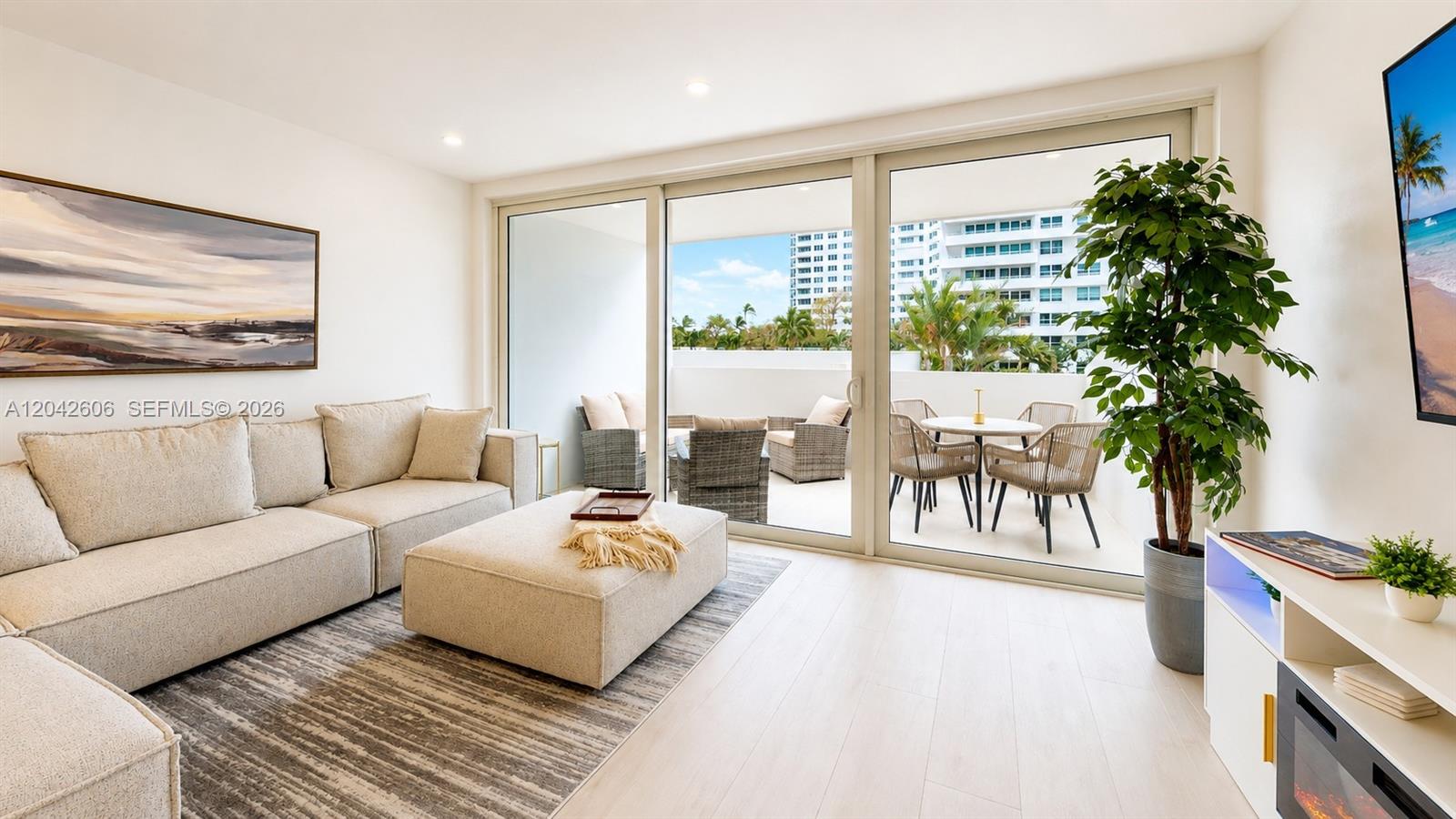 A modern living room features a beige sectional, large sliding glass doors, and a private balcony — 177 Ocean Lane Dr # 213, Key Biscayne FL 33149, KEY BISCAYNE, FL