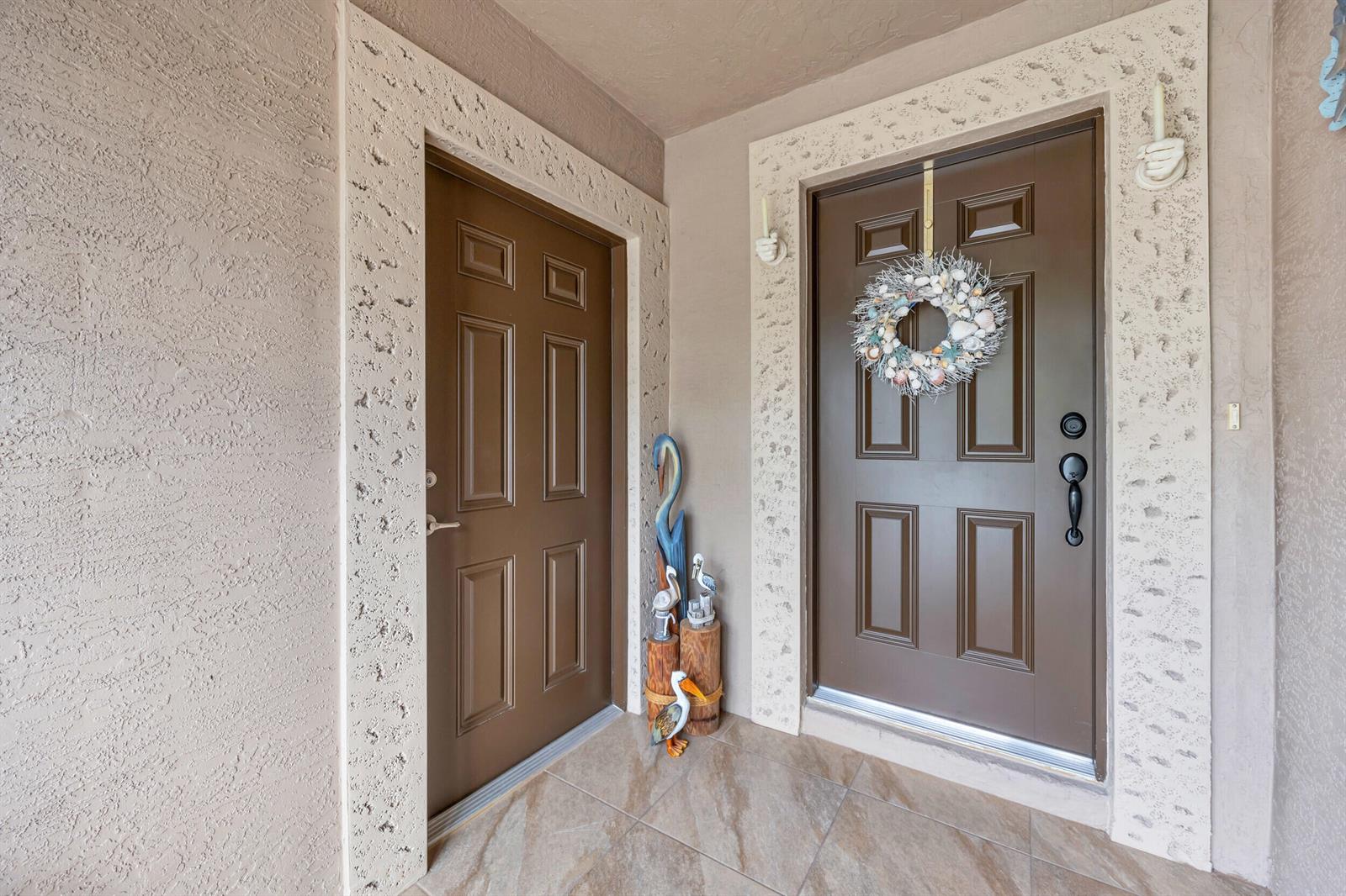 An entryway features two brown doors with textured stone trim and a coastal-themed wreath — 14961 Aguila, Fort Pierce FL 34951, FORT PIERCE, FL