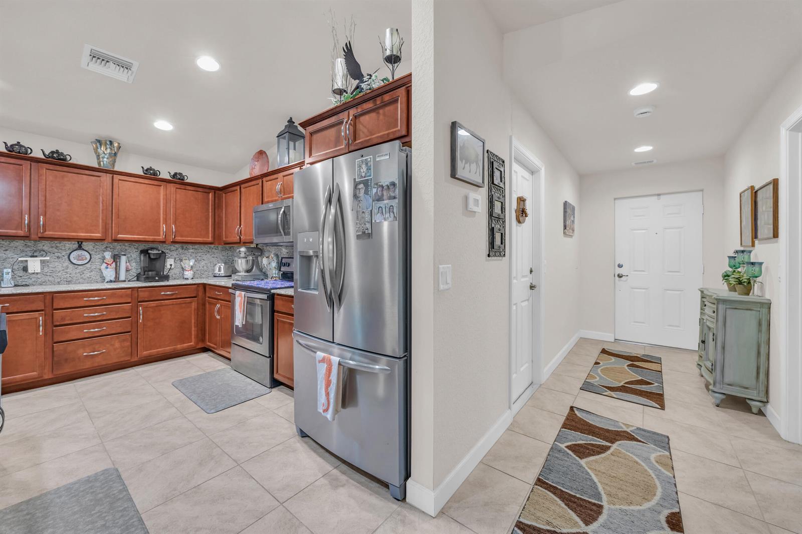 A kitchen with wood cabinets and stainless steel appliances sits beside an entryway hallway — 14961 Aguila, Fort Pierce FL 34951, FORT PIERCE, FL