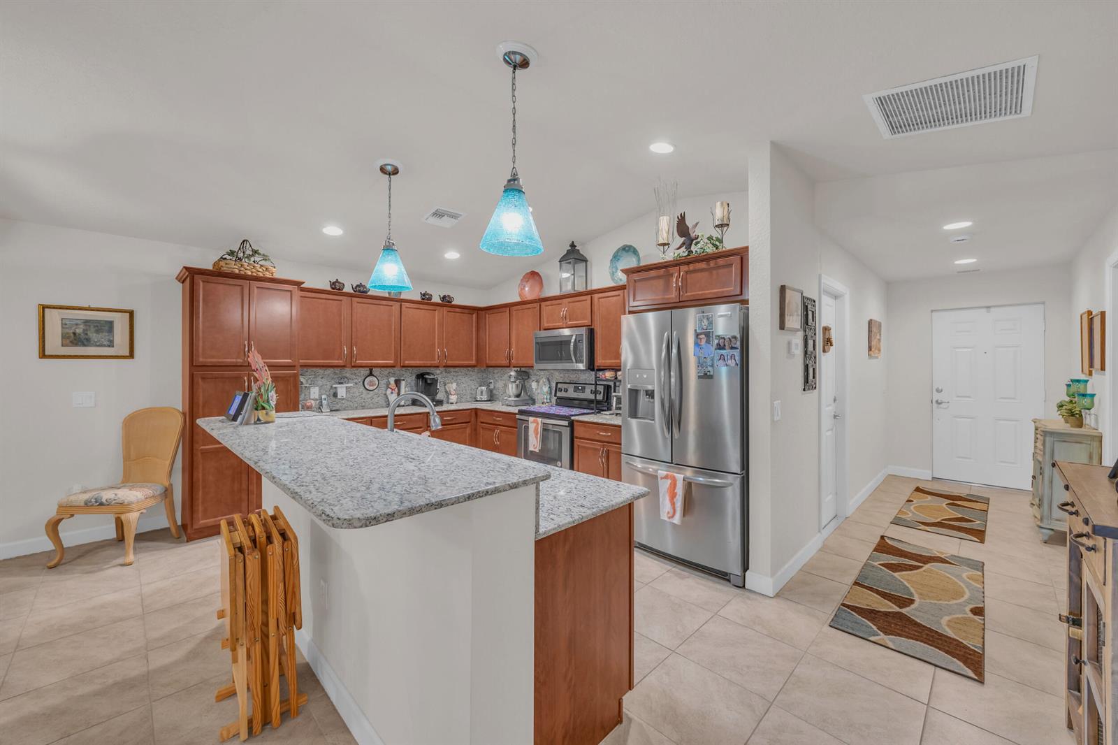 A kitchen features wood cabinets, granite countertops, stainless steel appliances, and a breakfast bar — 14961 Aguila, Fort Pierce FL 34951, FORT PIERCE, FL
