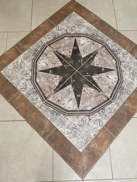 A decorative compass rose tile inlay is centered within a diamond-patterned floor design — 28 FIRETHORN LANE, PALM COAST, FL