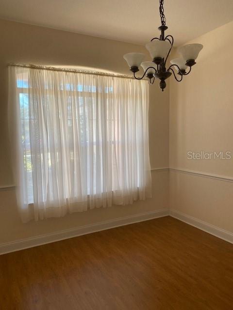 A dining room features wood-look flooring, white wainscoting, a large window with curtains, and a chandelier — 28 FIRETHORN LANE, PALM COAST, FL