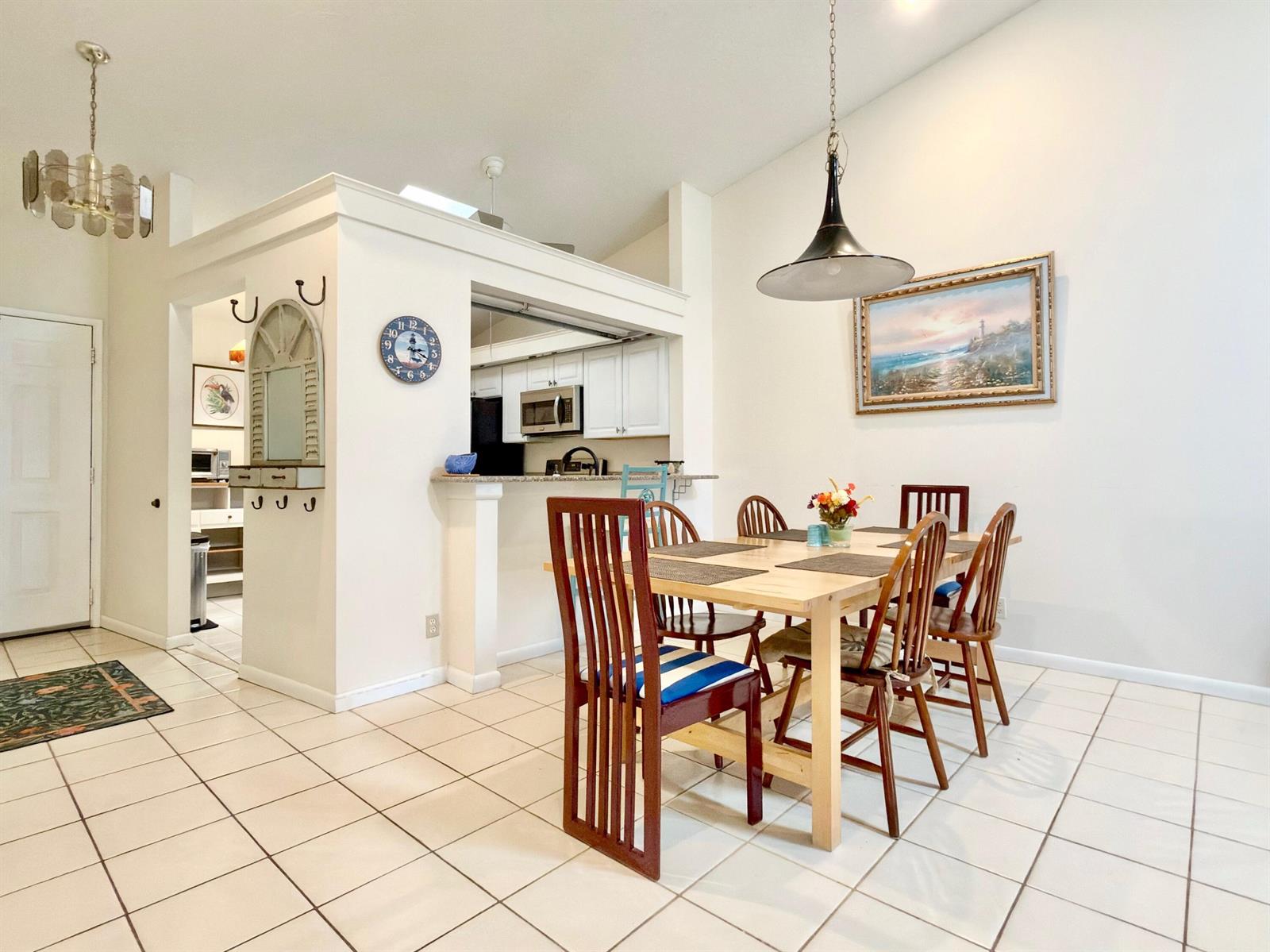 A dining area with a wooden table, six chairs, and a pass-through to the kitchen — 10975 Dolphin Palm Court # B, Boynton Beach FL 33437, BOYNTON BEACH, FL