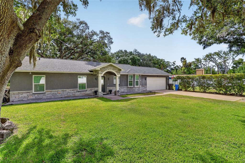 A single-story house with a gray exterior, stone veneer base, and a two-car garage — 7608 COPELAND ROAD, ODESSA, FL