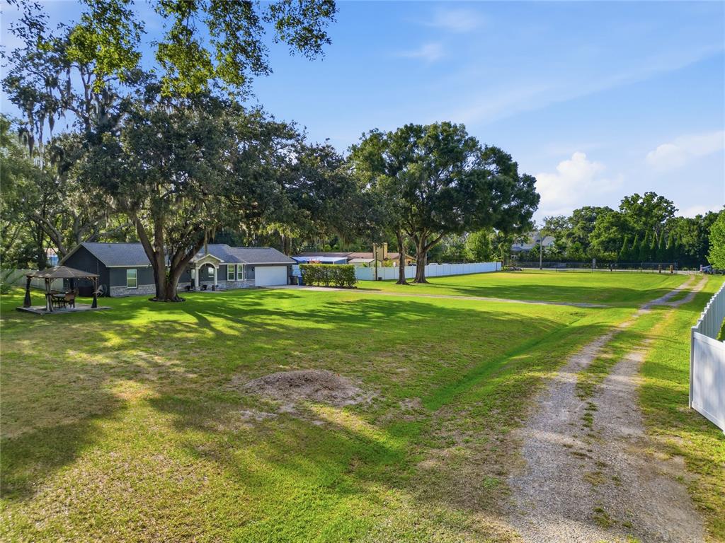 A large grassy yard features a house, a gazebo, and a gravel driveway — 7608 COPELAND ROAD, ODESSA, FL