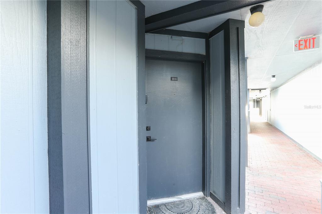 A dark gray apartment door with a number plate sits in a covered outdoor hallway — 3655 ATRIUM DRIVE UNIT 2, ORLANDO, FL