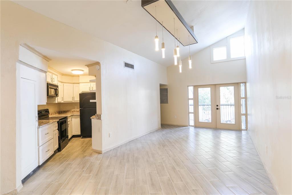 An open-concept living and dining area features light tile flooring, white walls, and a kitchen — 3655 ATRIUM DRIVE UNIT 2, ORLANDO, FL