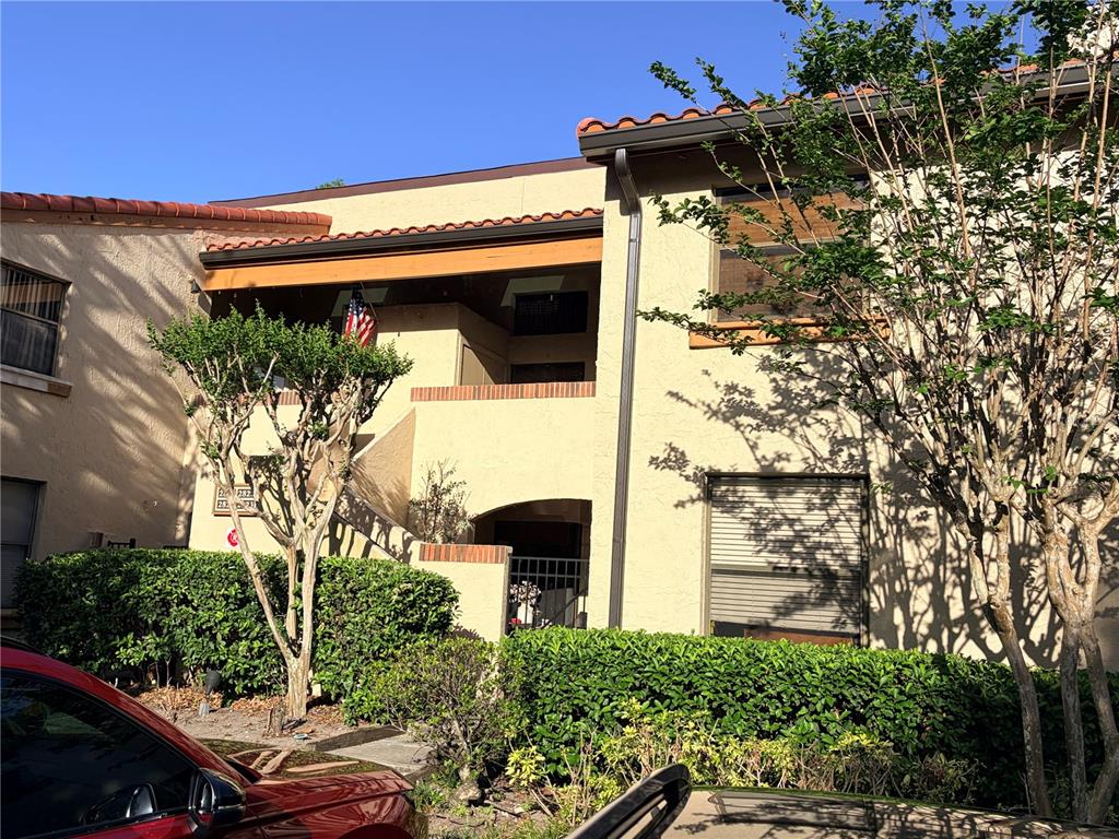 A two-story stucco apartment building with a tiled roof, balcony, and landscaped bushes — 2823 MARSALA COURT UNIT 2823, ORLANDO, FL