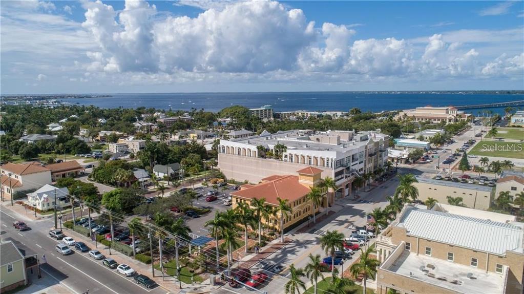 An aerial view shows a coastal town with buildings, palm trees, parking lots, and water — 109 TAYLOR STREET UNIT 2, PUNTA GORDA, FL