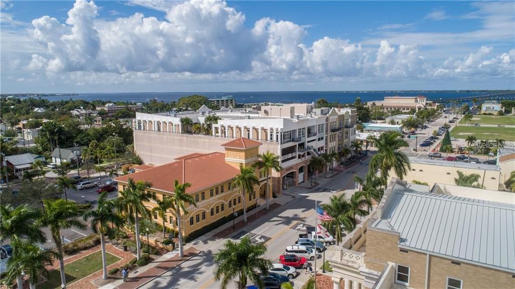 An aerial view shows a yellow building, a multi-story parking structure, and palm-lined streets — 109 TAYLOR STREET UNIT 2, PUNTA GORDA, FL