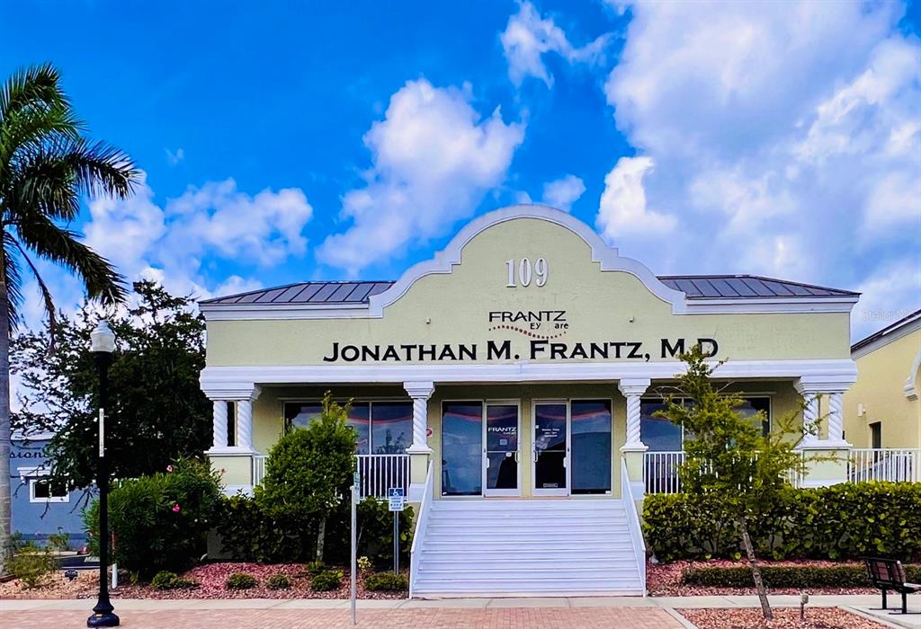 A single-story commercial building with a light green facade, white columns, and a central staircase — 109 TAYLOR STREET UNIT 2, PUNTA GORDA, FL