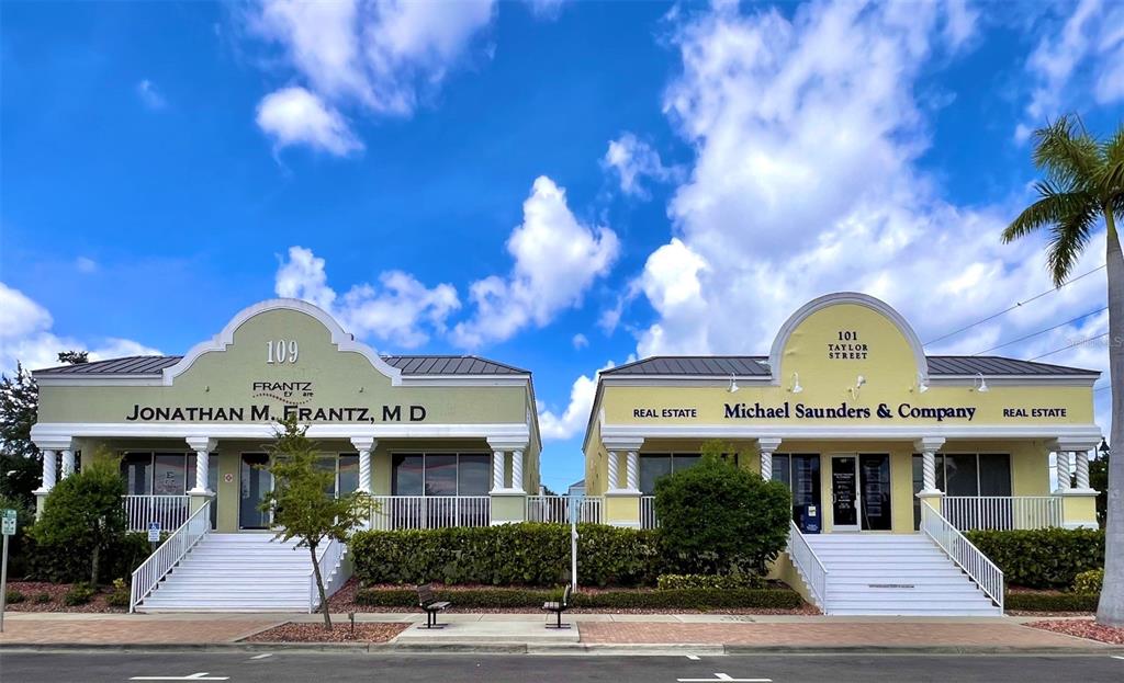 Two adjacent yellow commercial buildings with white stairs and arched rooflines under a blue sky — 109 TAYLOR STREET UNIT 2, PUNTA GORDA, FL