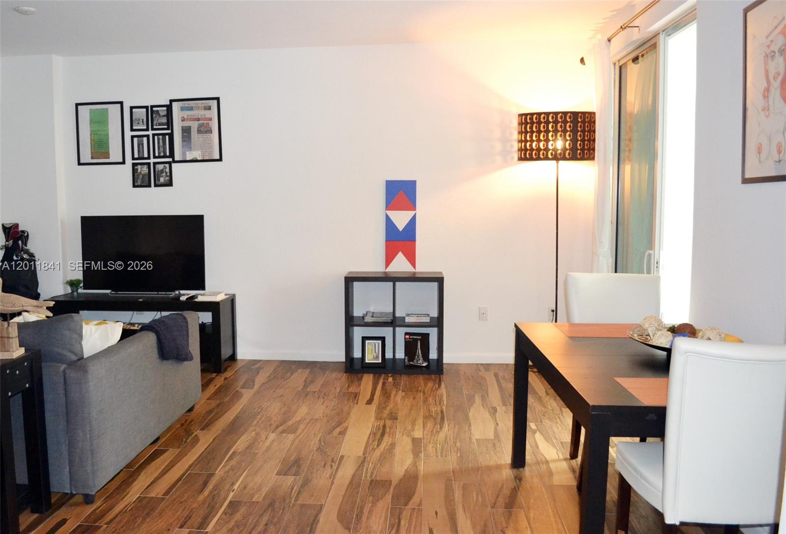 A living and dining area features wood-look tile flooring, a television, and a floor lamp — 1830 Radius Dr # 317, Hollywood FL 33020, HOLLYWOOD, FL