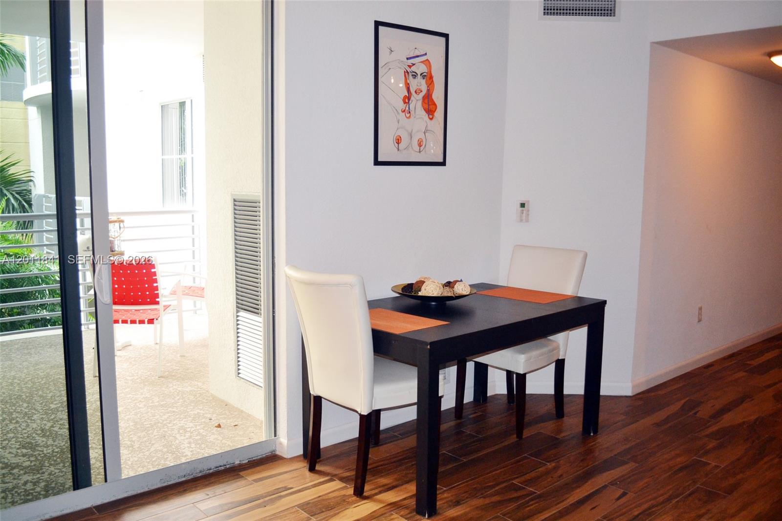 A dining area features a dark table, two white chairs, and a framed wall print — 1830 Radius Dr # 317, Hollywood FL 33020, HOLLYWOOD, FL